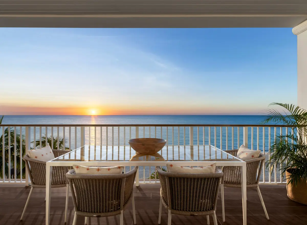 A dining table on a Beaches Negril balcony overlooking the sea at sunset