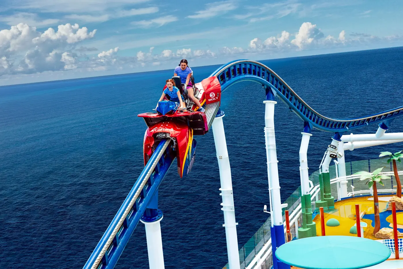 Guests riding the BOLT roller coaster above a Carnival ship’s deck.