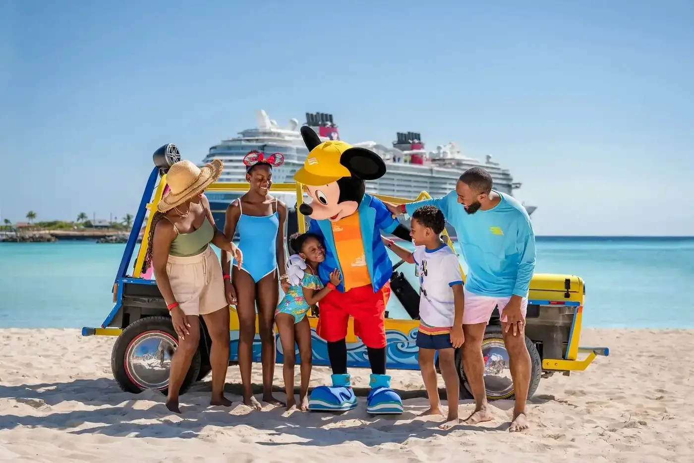 A family with Mickey Mouse at Castaway Cay, with a Disney cruise ship behind them.