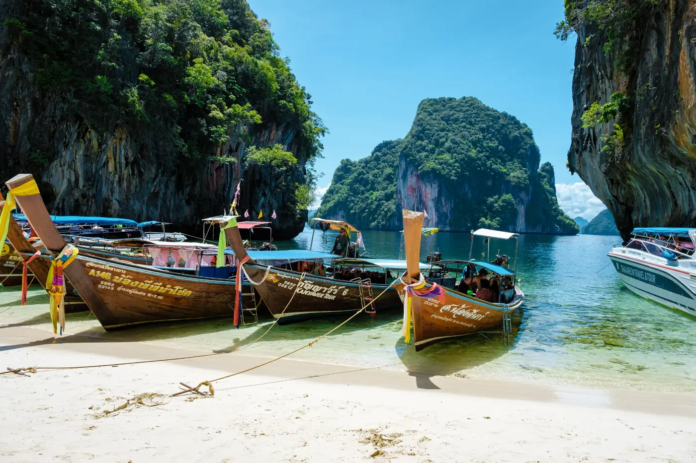 Longtail boats in a sheltered bay framed by limestone cliffs in Thailand