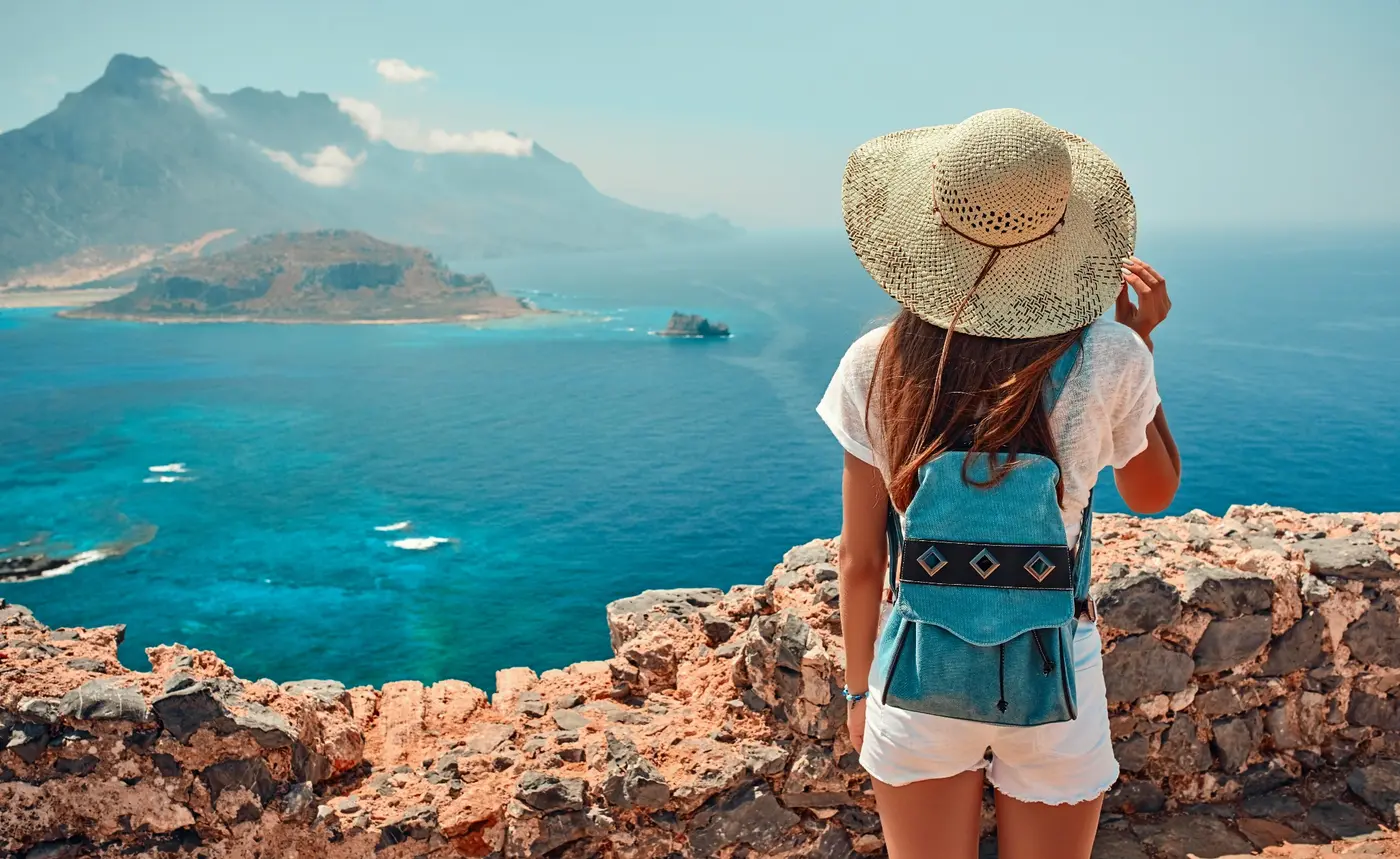A traveler taking in a turquoise bay from a coastal overlook