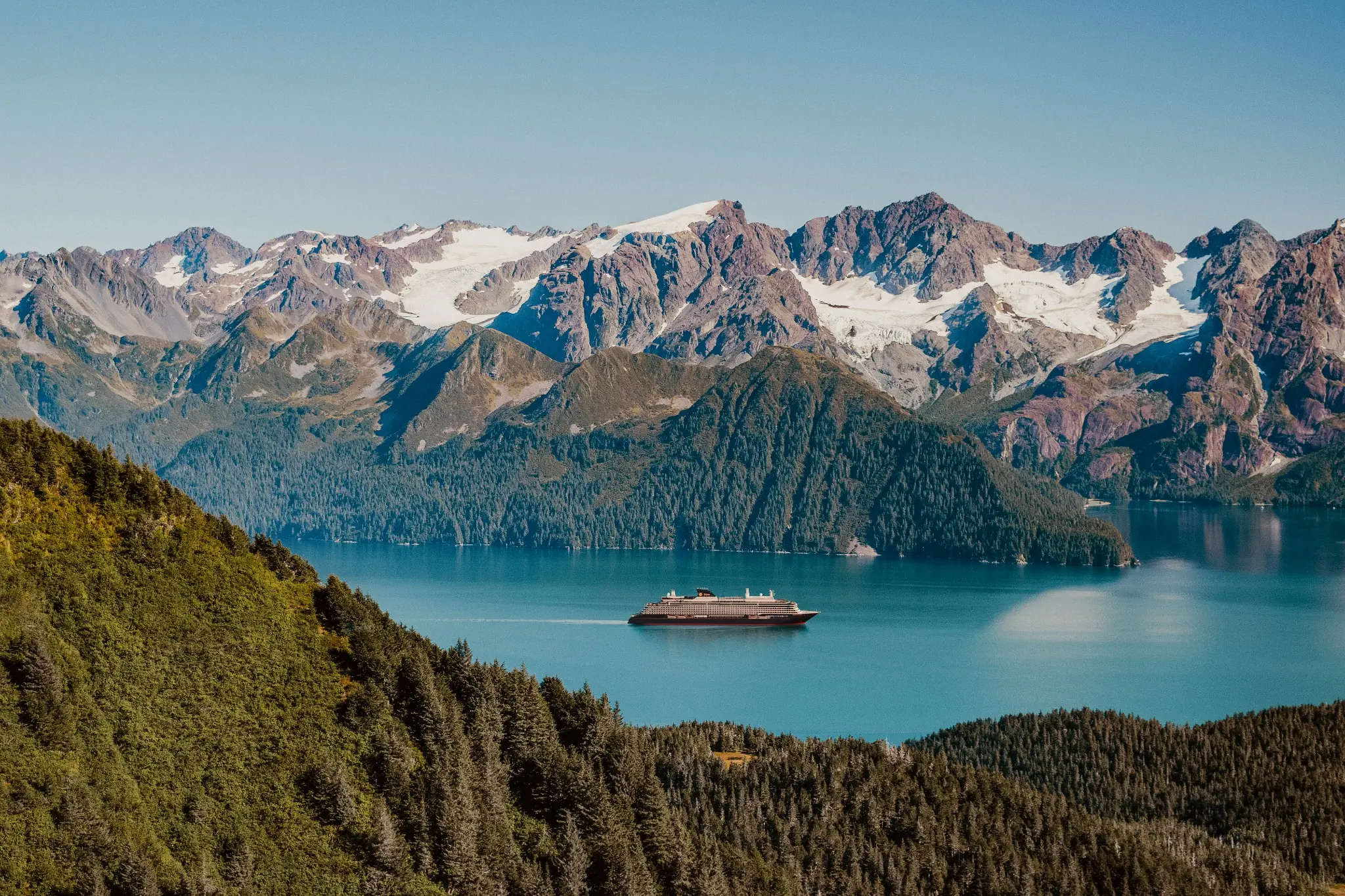 An Explora ship on calm water surrounded by Alaska’s mountains