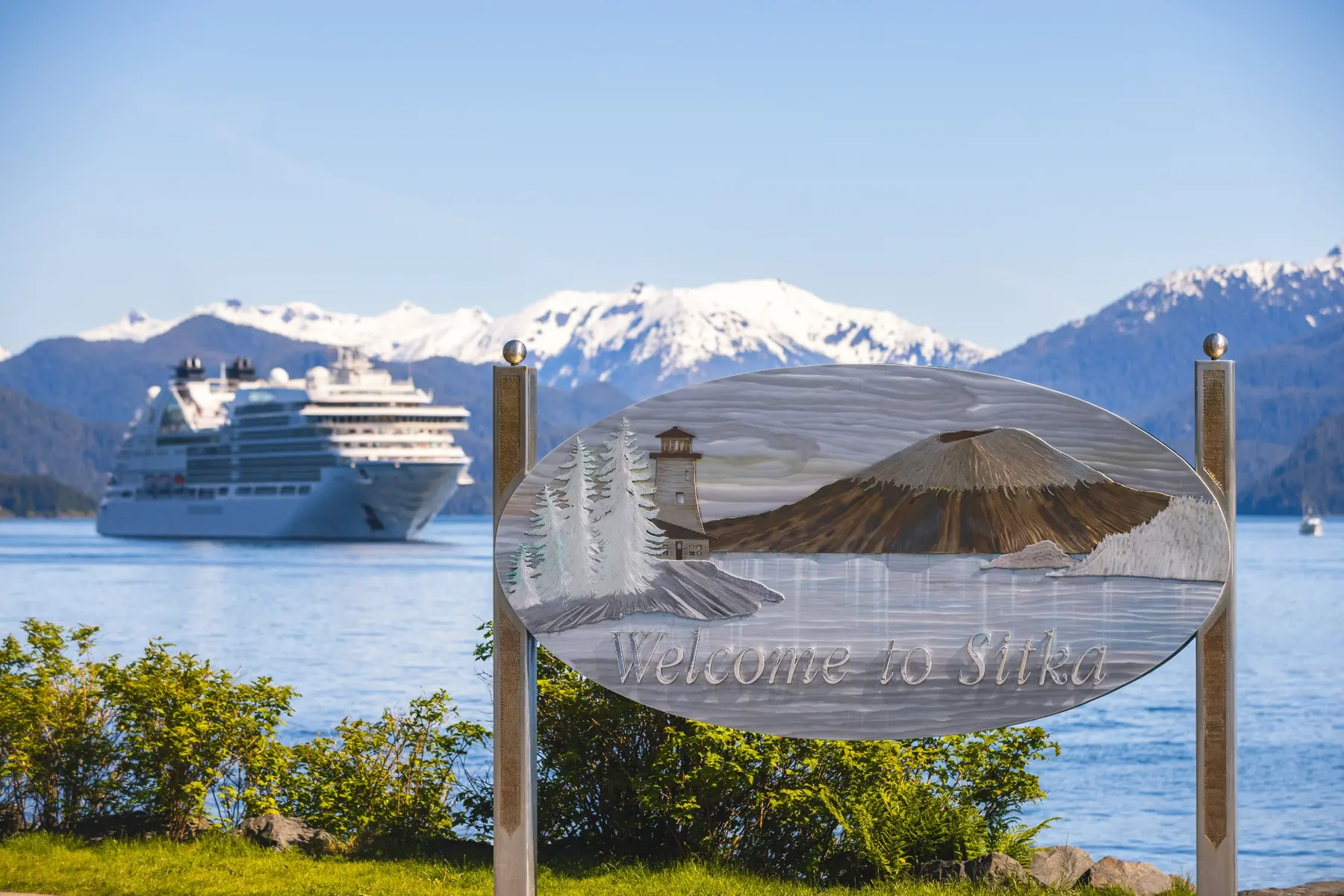 A Holland America ship in an Alaska harbor beside a welcome sign.