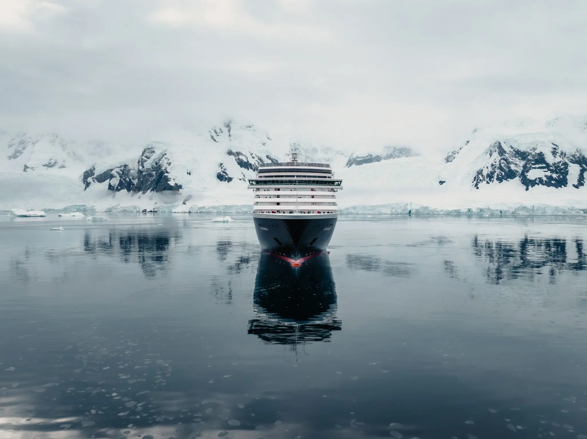 A Holland America ship surrounded by Antarctic mountains and ice.