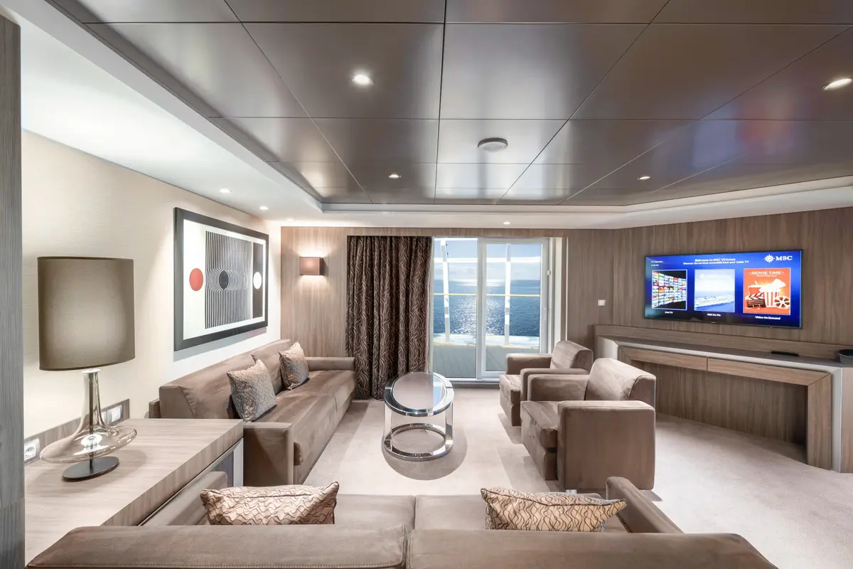 A spacious MSC suite living room with a balcony beyond