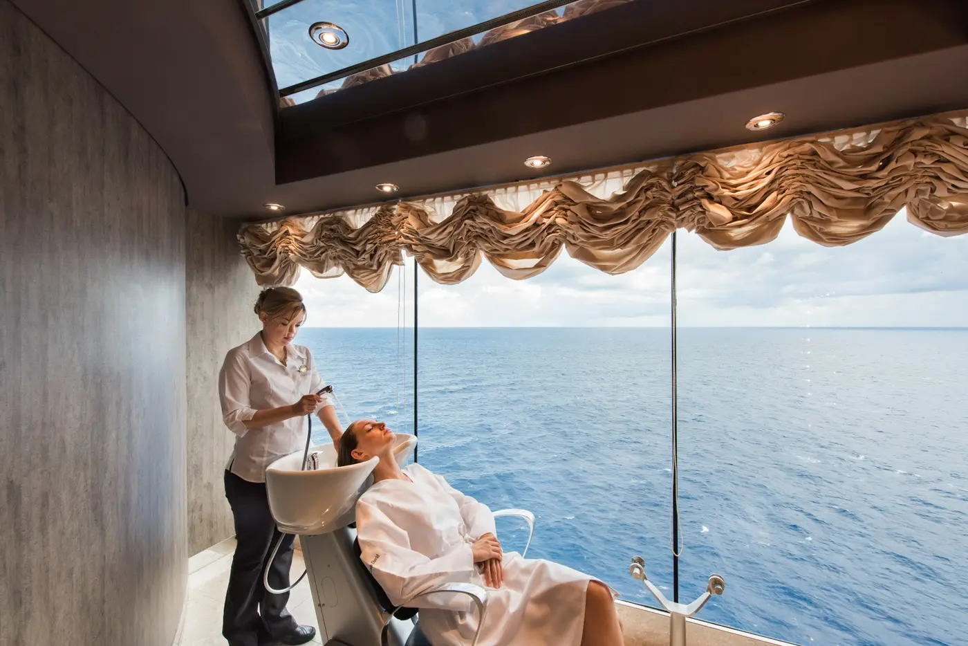 A guest enjoying a salon treatment beside a window overlooking the sea