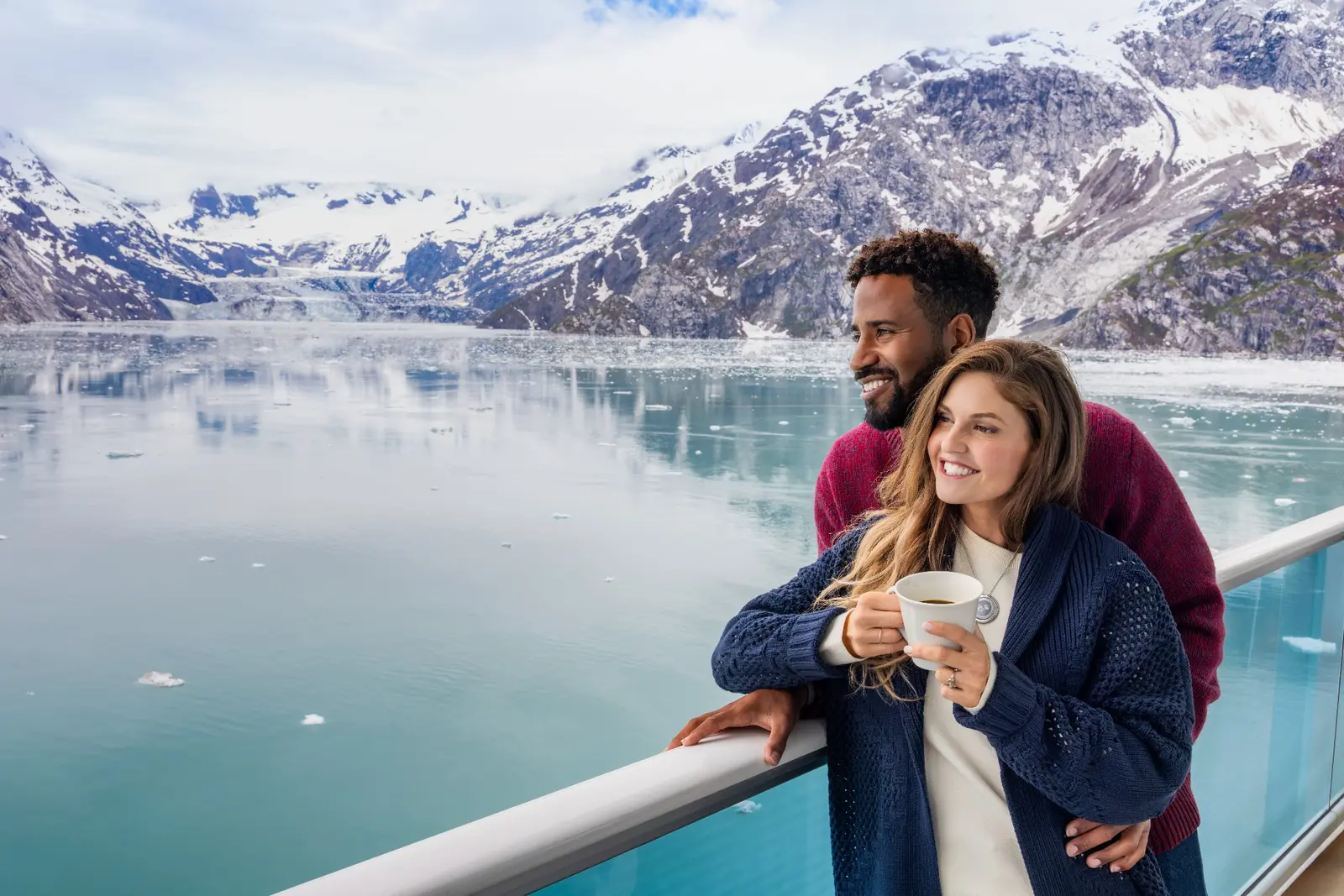 A couple on a Princess ship’s balcony overlooking a glacier.
