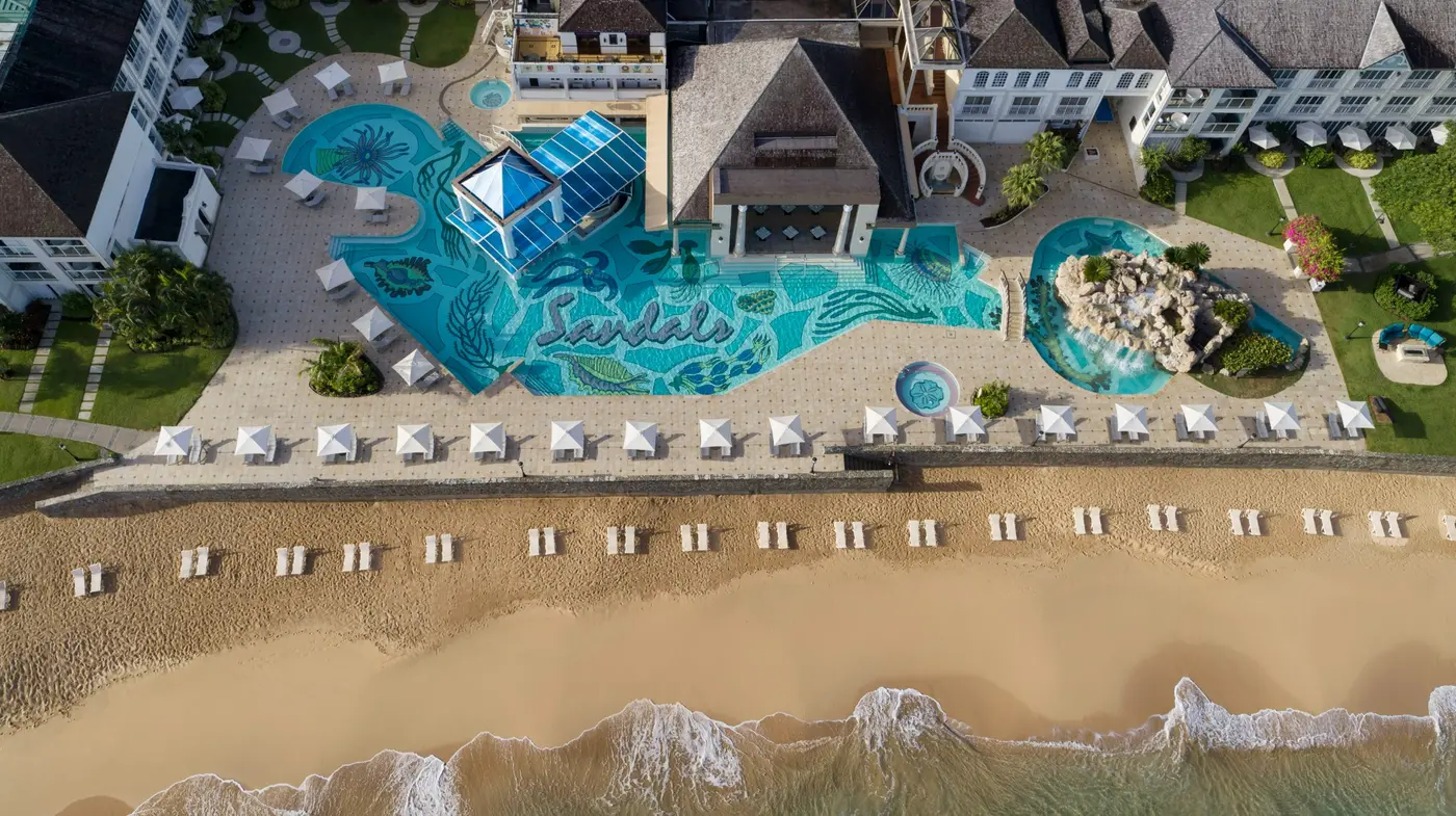 A Sandals pool and palm-lined beach seen from above