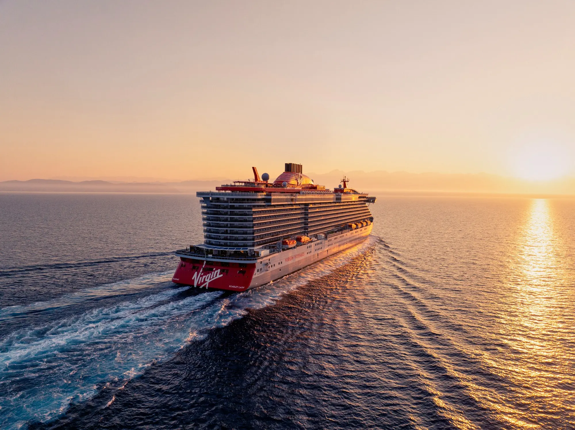 A Virgin Voyages ship sailing into the sunset.