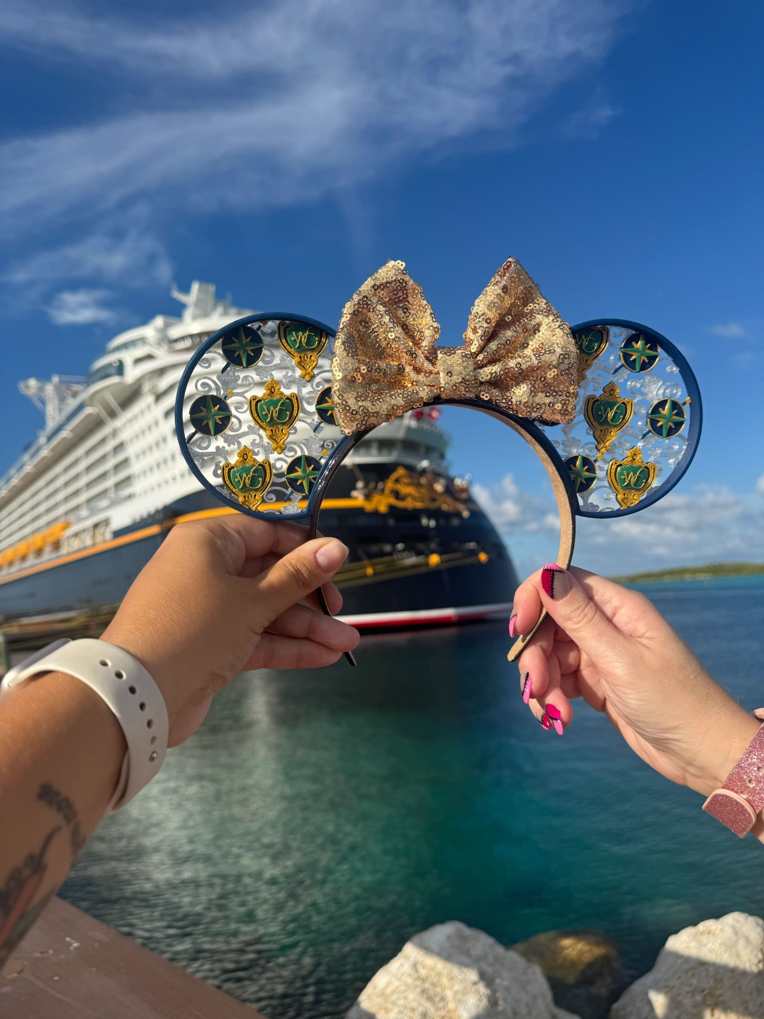 Disney ears held in front of a Disney cruise ship