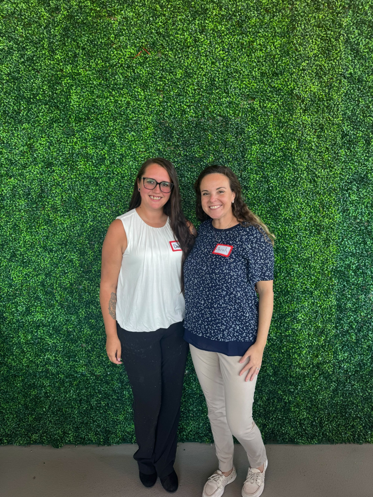 Two advisors together in front of a green wall