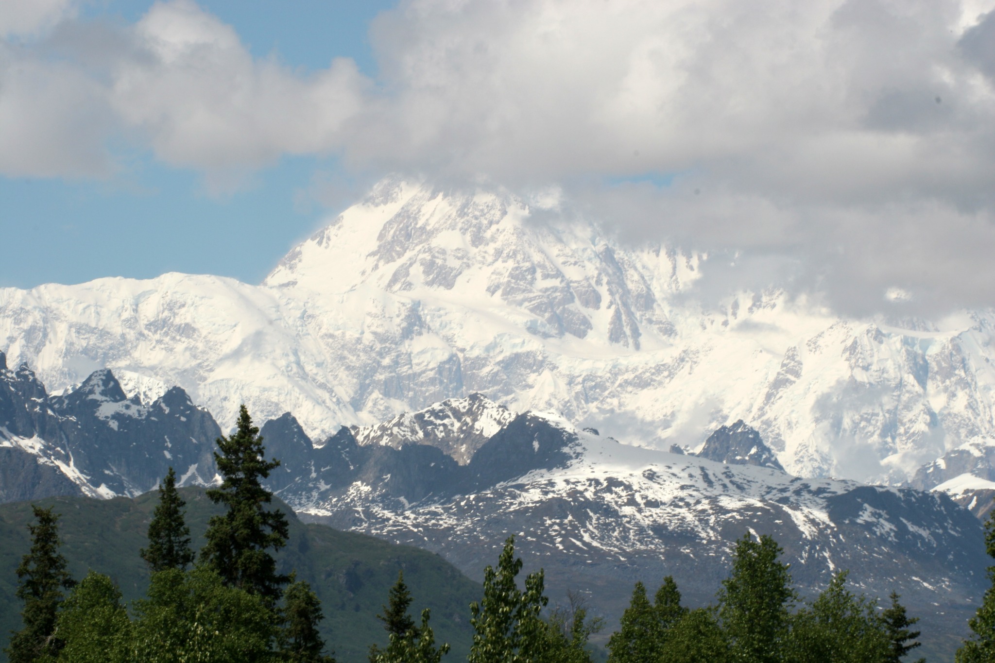 Denali rising above Alaska’s landscape with snow-covered peaks and clouds.